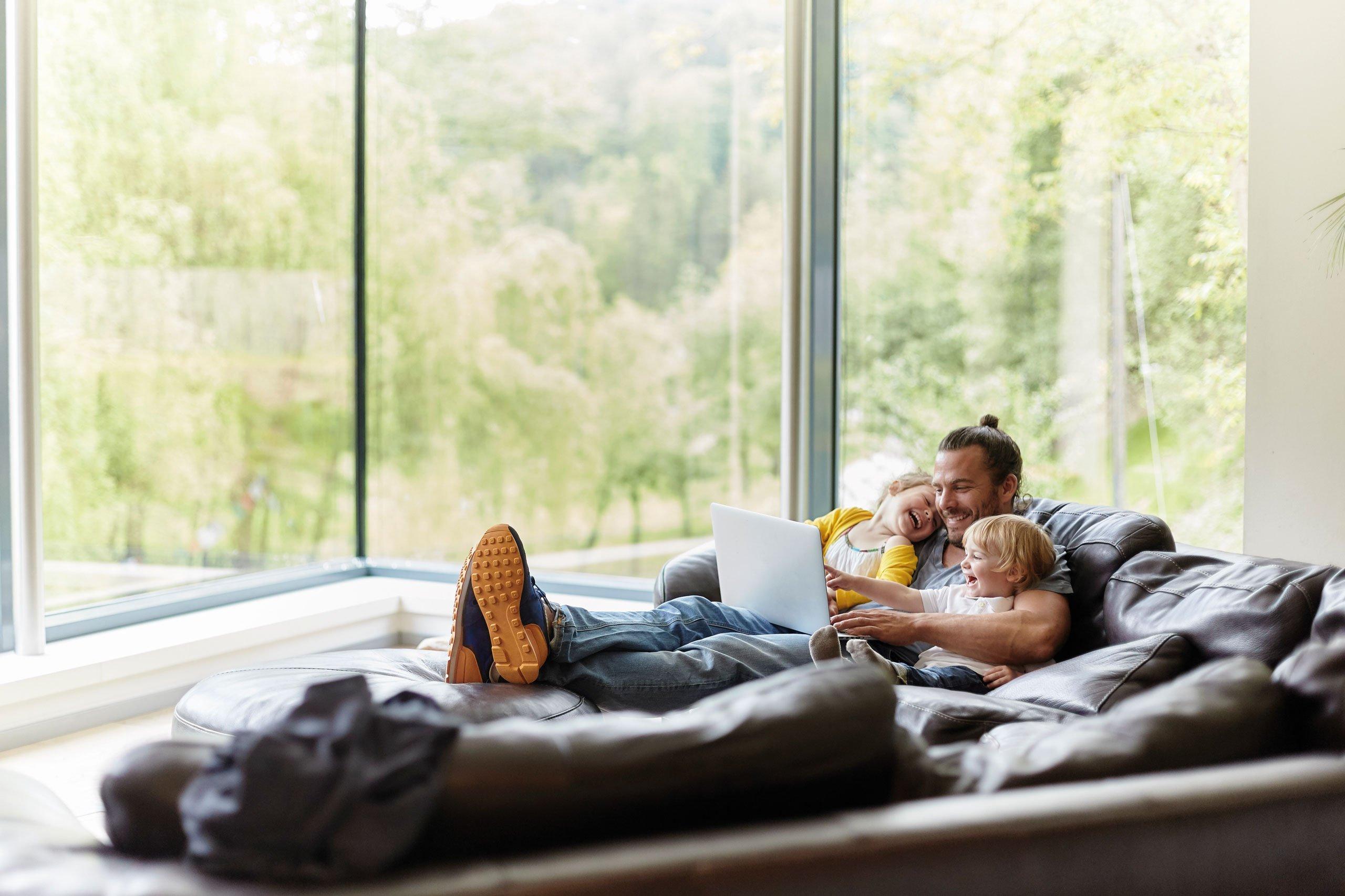 Far og barn som sitter i en sofa og ler