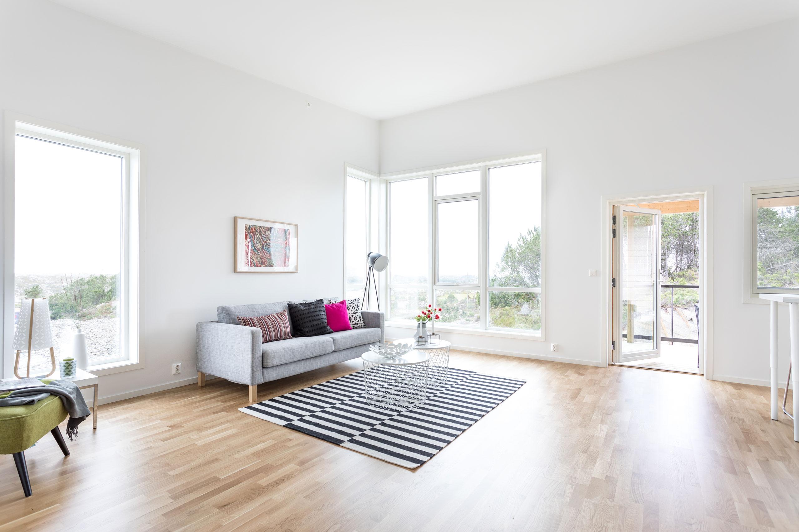 Stort og lyst oppholdsrom med moderne møblement og mange vinduer som slipper inn mye naturlig lys